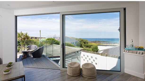 Ein modernes Zimmer mit einer großen Schiebeglasdoor, die auf einen Balkon mit Meerblick führt.
