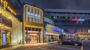 A hotel with a modern facade, a staircase leading to the entrance, and a car parked in front.