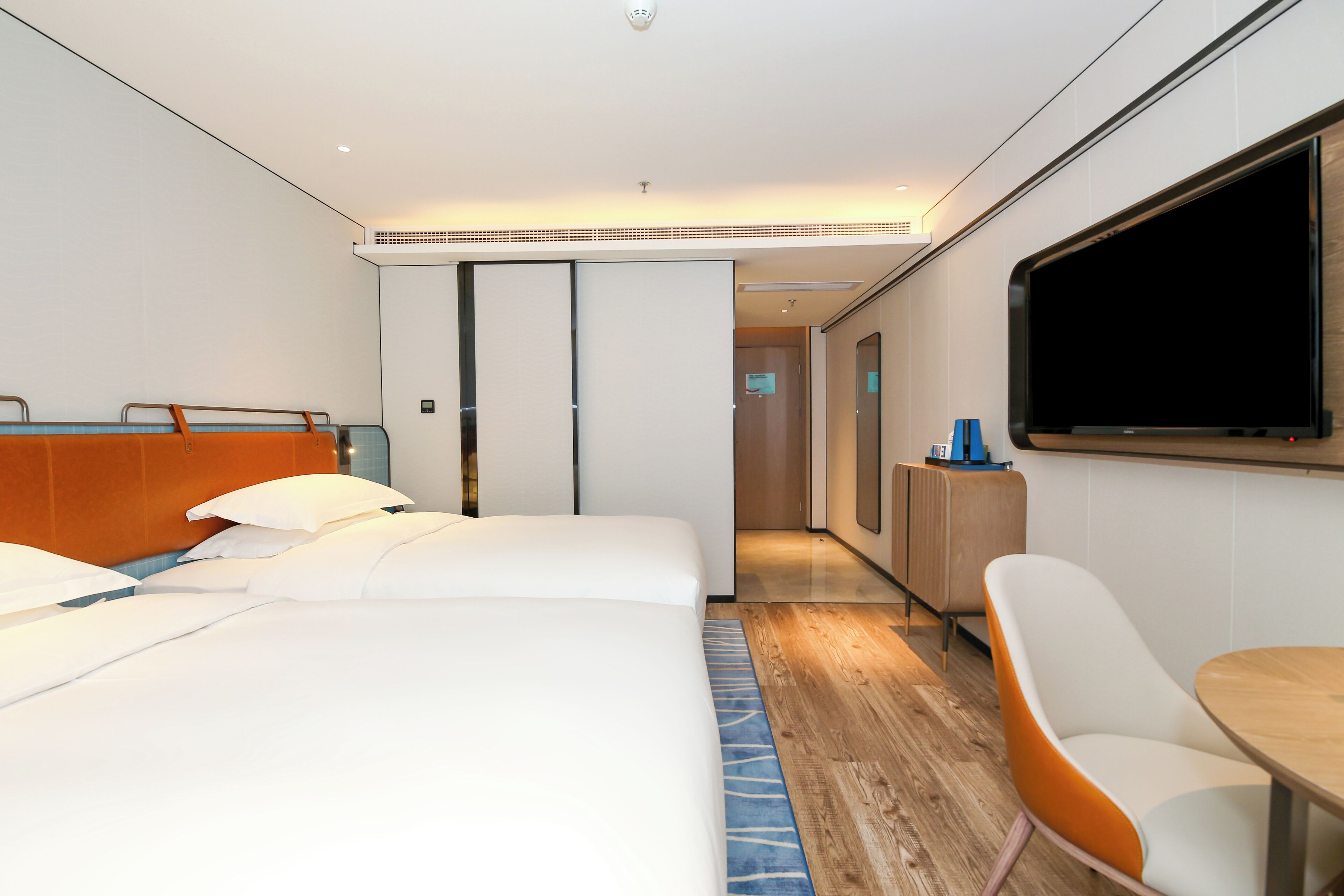 A hotel room with a bed, a desk, a chair, and a TV.