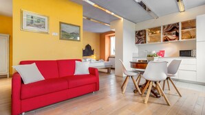 Uma sala de estar moderna com um sofá vermelho, cadeiras brancas e um espaço para refeições.