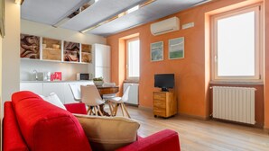 Uma sala de estar moderna com um sofá vermelho, um armário de madeira e uma televisão.