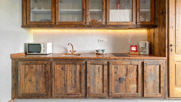 Een keuken met houten kastjes, een magnetron, een spoelbak en een koffiezetapparaat.