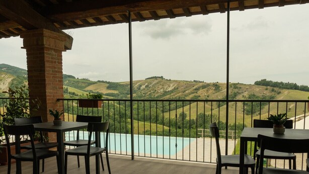 Una terraza con vistas a un lago y colinas, con una mesa y sillas.