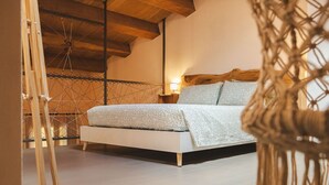 Un dormitorio con cama, vigas de madera, mesita de noche y lámpara.