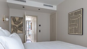 A bedroom with a large bed, a door leading to a balcony, and two abstract wall art pieces. - Marais - One Bedroom in Paris (Paris)