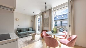 A modern living room with a sofa, a dining table with chairs, and a view of the outside balcony. - Marais - One Bedroom in Paris (Paris)
