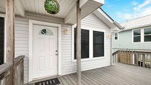 A house with a white front door, a small porch, and a wooden deck.