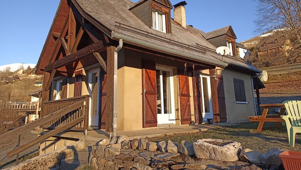 Ein Chalet mit steilem Dach, Holzfassade und Steinunterbau.