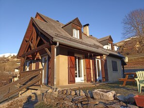 Ein Chalet mit steilem Dach, Holzfassade und Steinunterbau.