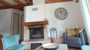 Ein Wohnzimmer mit Kamin, Holzbalken, einer Uhr und einem Sofa.