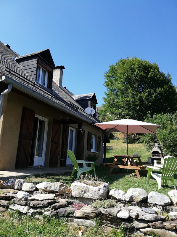 A house with a stone wall, a patio with a table and chairs, and a chimney.
