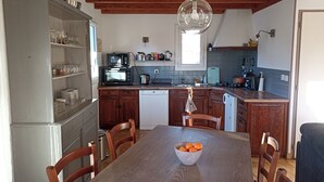 Eine Küche mit Holzausstattung, einem Esstisch mit Stühlen, einer Schüssel Orangen und einer Pendelleuchte.
