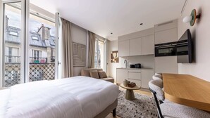 Una habitación de hotel moderna con una cama grande, un sofá, una mesa de comedor y una zona de cocina.