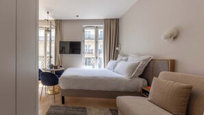 A modern hotel room with a bed, a sofa, a TV, and a balcony view. - Marais - 2 Bedrooms 2 Living rooms in Paris (Paris)