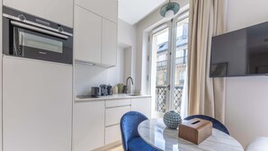 A modern kitchen with a Siemens oven, a dining area with a marble table, and a view of a balcony with a cityscape. - Marais - 2 Bedrooms 2 Living rooms in Paris (Paris)