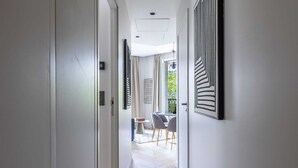 A modern hallway with a light wood floor, white walls, and a dining area with a table and chairs. - Marais - 2 Bedrooms 2 Living rooms in Paris (Paris)