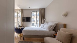 Une chambre d’hôtel moderne équipée d’un lit, d’un canapé, d’une télévision et offrant une vue sur le balcon.