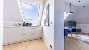 Une cuisine moderne avec des meubles blancs, une fenêtre et un parquet en bois disposé en chevrons.
