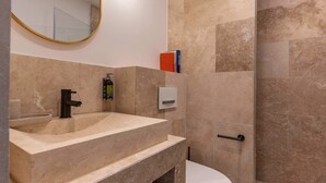 Un baño moderno con un lavamanos color beige, un inodoro y una zona de ducha.