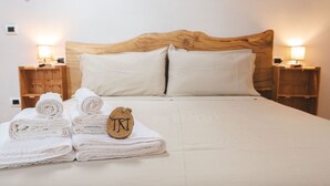 Una cama bien hecha con cabecera de madera, dos mesitas de noche con lámparas y un cartel sobre la cama.