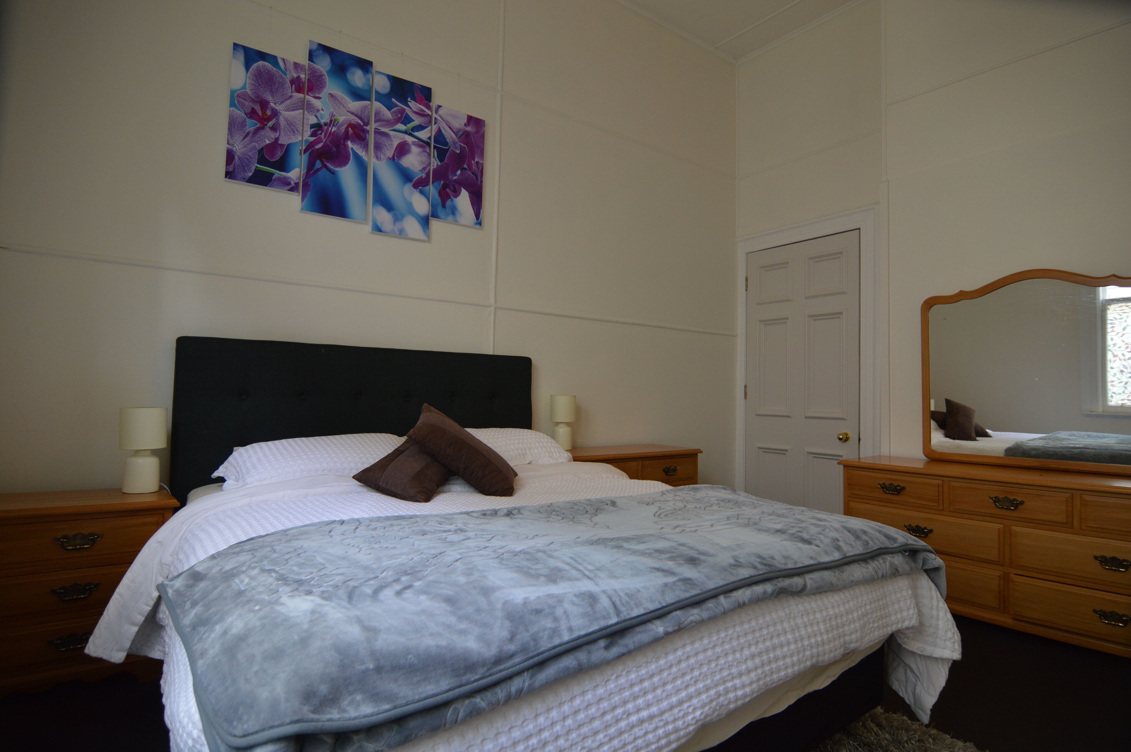 Ein Schlafzimmer mit Bett, Nachttisch, Kommode und Tür.