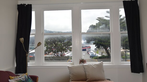 A room with a large window overlooking a parking area and trees.