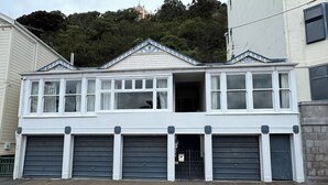 A two-story building with a garage entrance, large windows, and a steeply pitched roof.