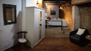 Ein Zimmer mit einem Bett, einem Sessel, einem kleinen Tisch und einem Kleiderschrank.