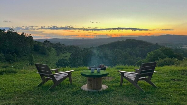 A picnic setup with two wooden chairs and a table on a grassy hill overlooking a valley during sunset. - Tiny Home in Hampton (Hampton)