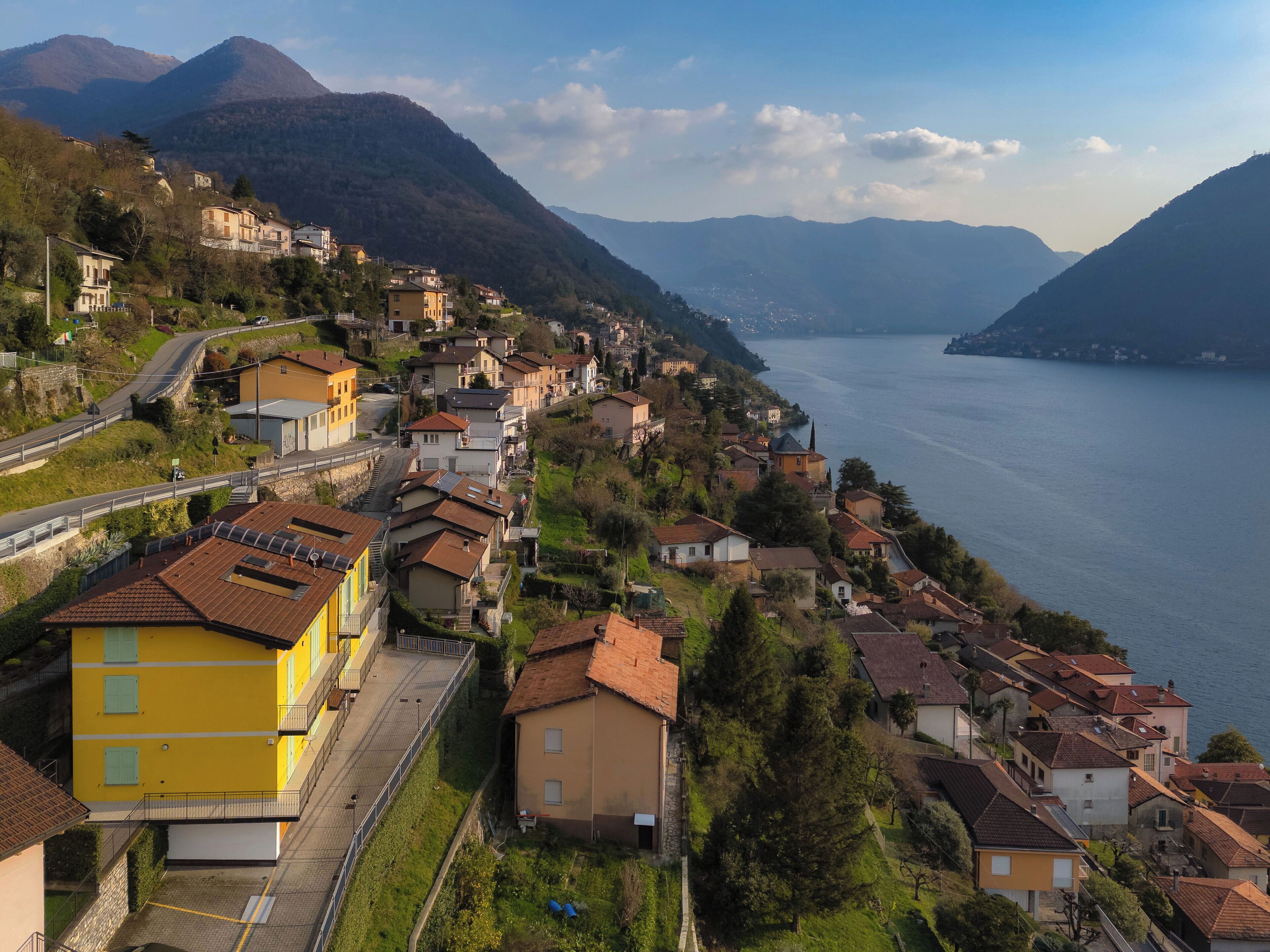 A coastal town with terraced houses, a road, and a lake.