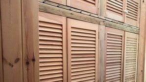 A set of wooden louvered closets with metal handles, likely part of a hotel room's interior. - Persea House. Ideal for families and lovers of Bologna and its peace. (Tarifa)