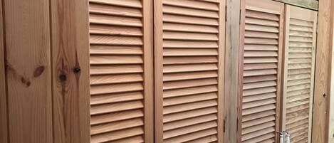 Conjunto de armarios con puertas de madera rejilla y tiradores metálicos, probablemente parte del interior de una habitación de hotel.