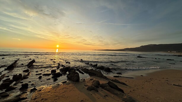 A beach with rocks in the foreground and a sunset in the background. - Persea House. Ideal for families and lovers of Bologna and its peace. (Tarifa)