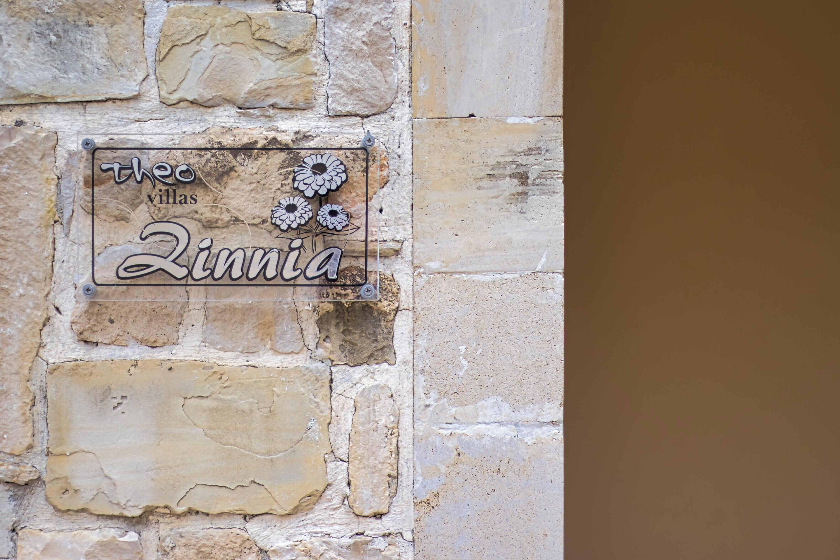 A stone wall with a sign that reads "The Villas Zinnia."