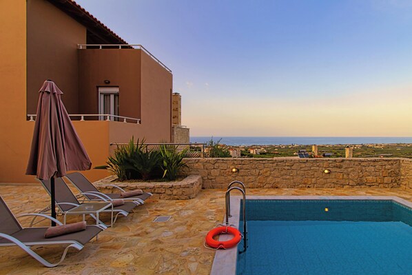 A pool area with lounge chairs and a lifebuoy, overlooking a coastal view. - Theo Villas With Sea View (Marathokefala)