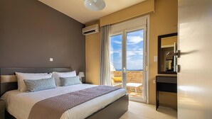 Une chambre dotée d’un grand lit, d’une table de chevet, d’un bureau et d’une porte-fenêtre coulissante donnant sur un espace extérieur.