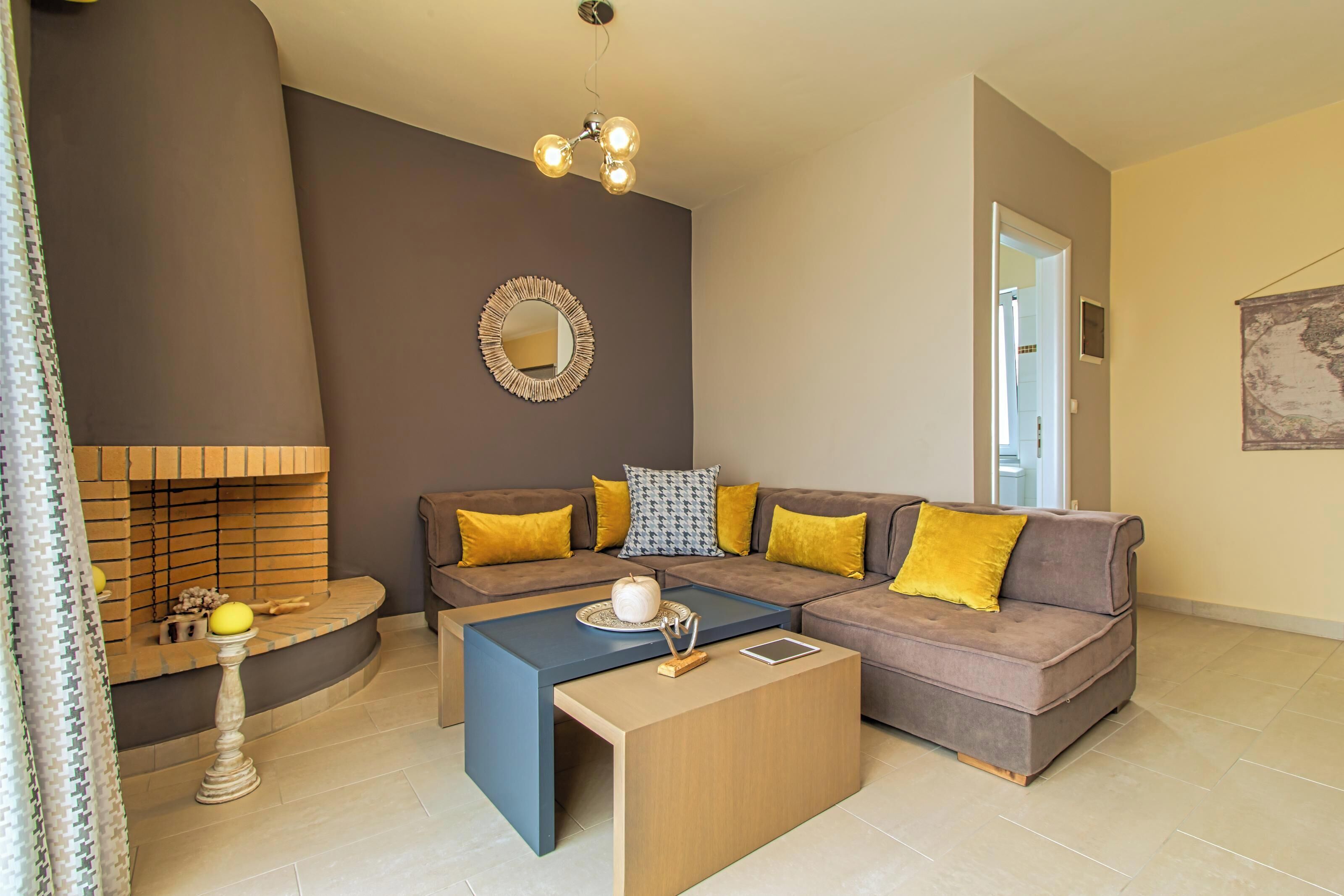 A living room with a sectional sofa, a coffee table, a fireplace, and a mirror on the wall.