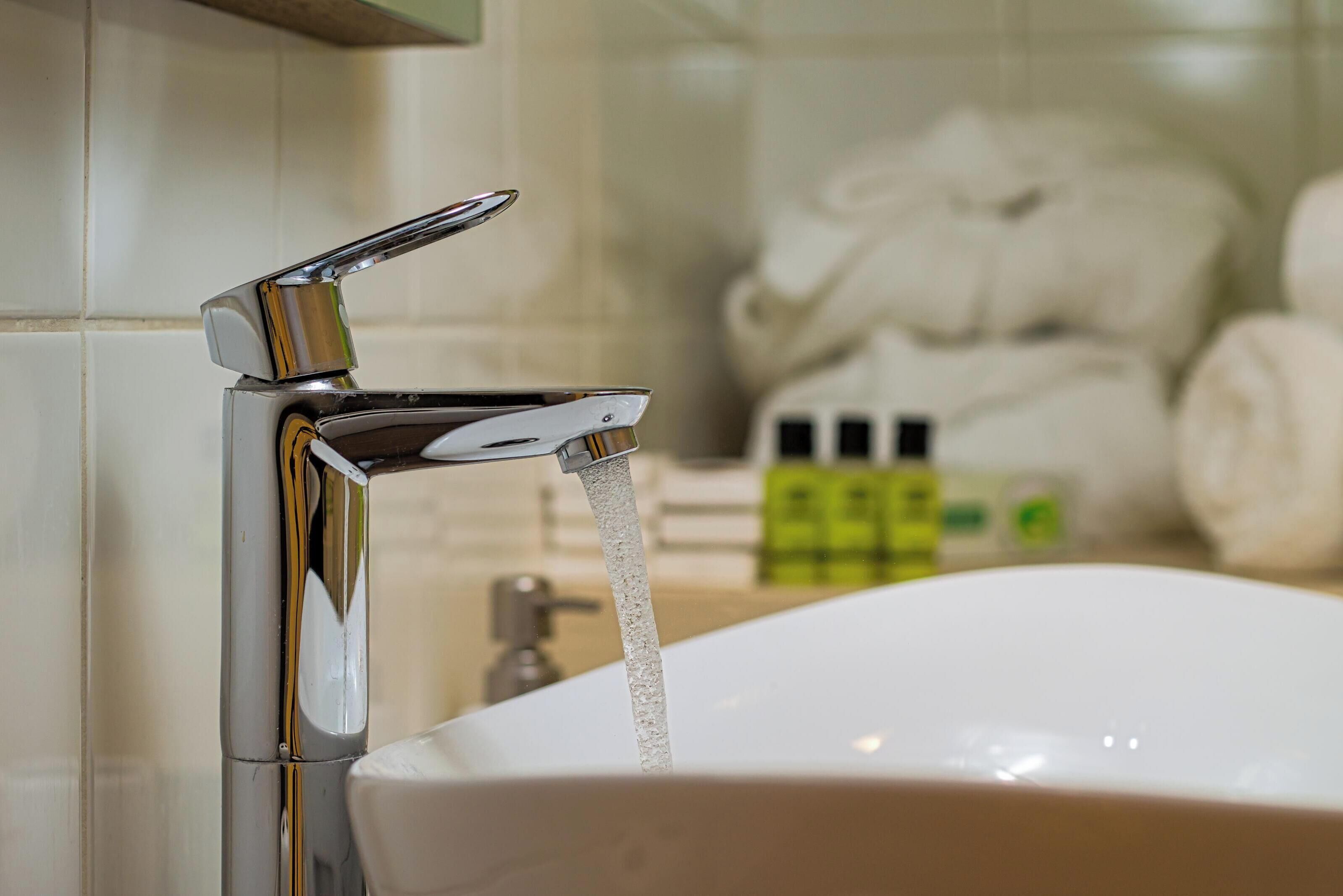 A bathroom with a chrome faucet and a white sink.