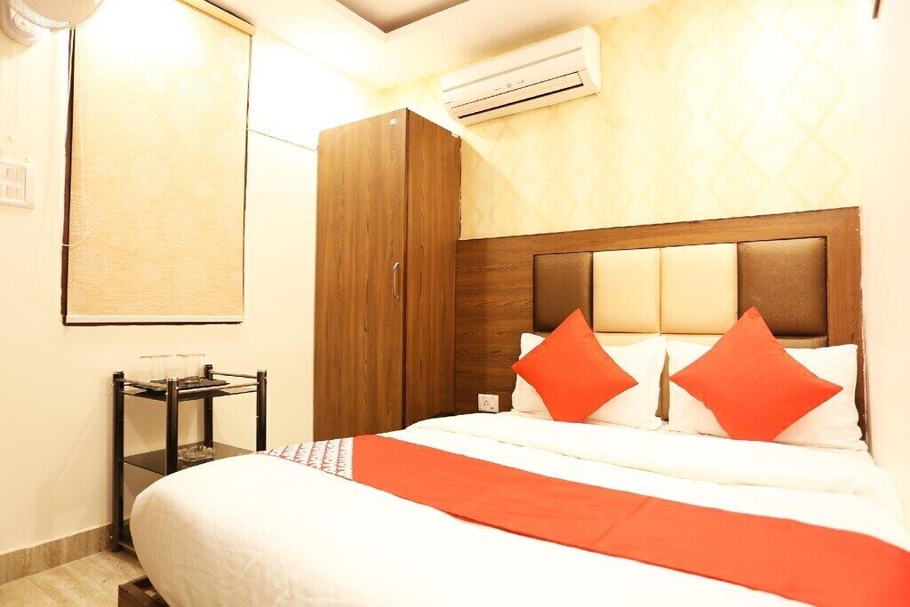 A hotel room with a bed, a wardrobe, a bedside table, and an air conditioning unit.