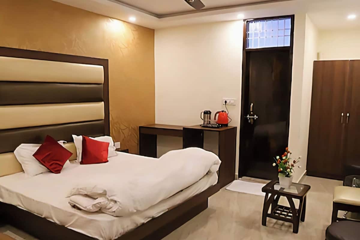 A modern hotel room with a large bed, bedside tables, a desk, and a wardrobe.
