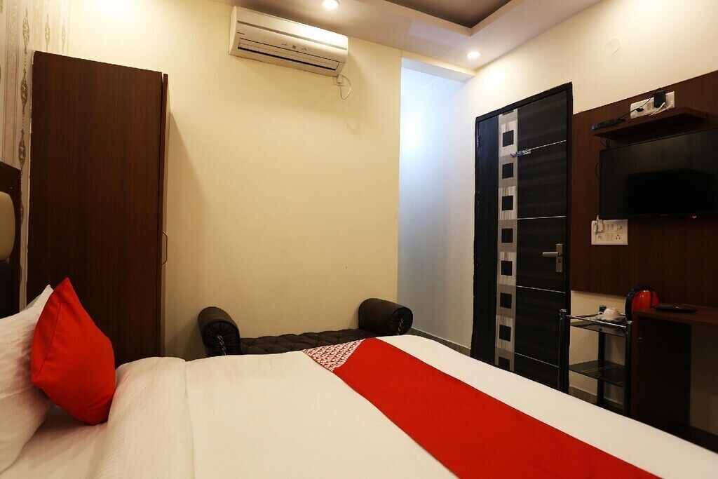 A hotel room with a bed, a wardrobe, a TV, and an air conditioning unit.