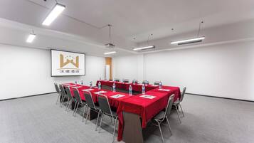 A conference room with a long table, chairs, and a projector screen.