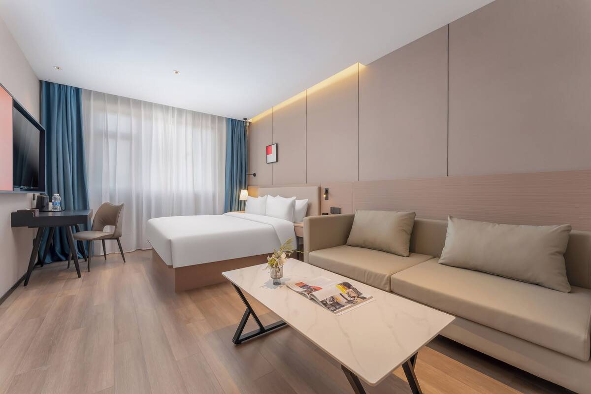 Una habitación de hotel moderna con una cama, un sofá, un escritorio y una mesita de café.