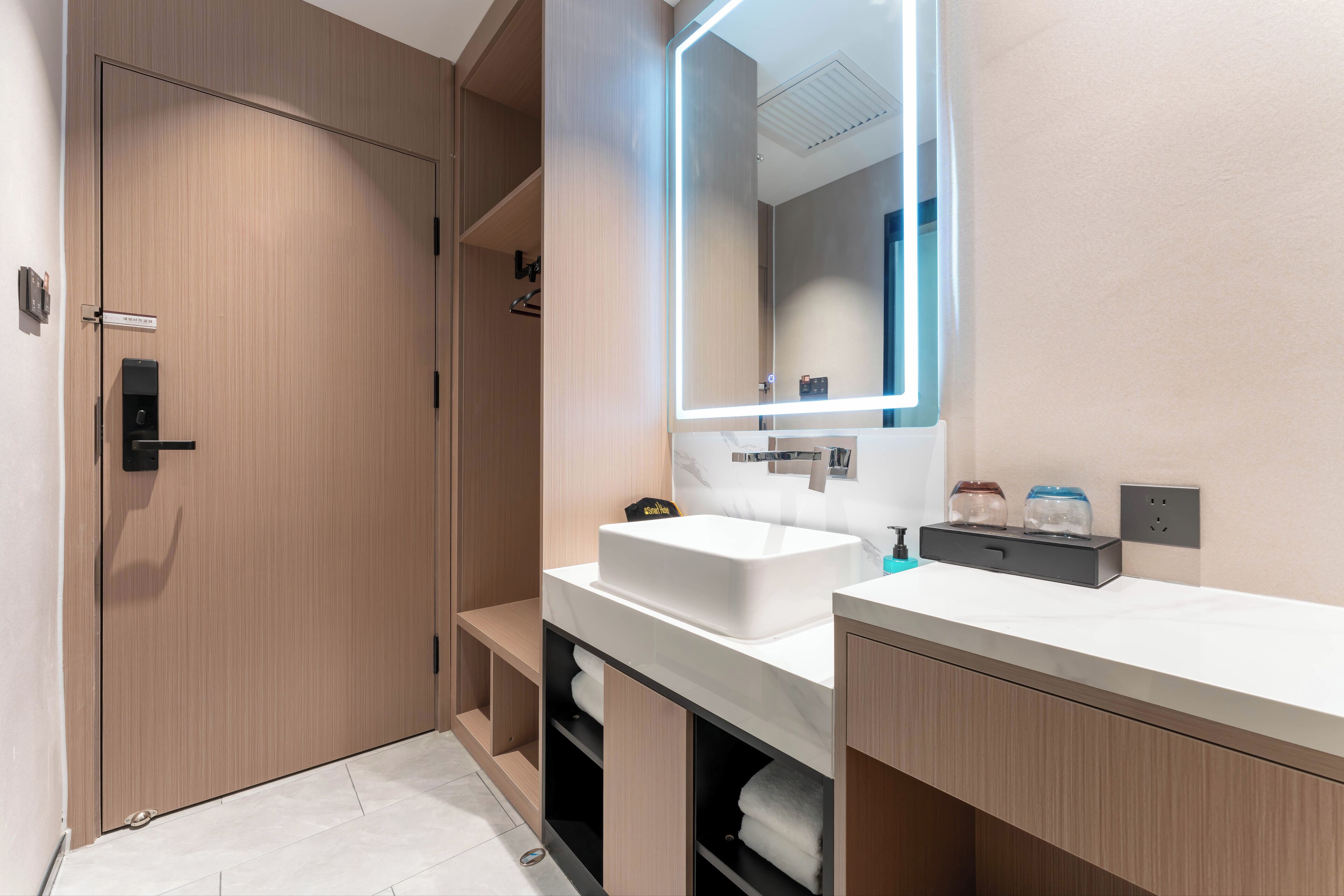 A modern bathroom with a large mirror, a white sink, and a towel rack.