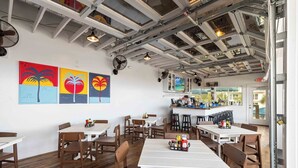 A restaurant with wooden tables and chairs, a bar area, and artwork on the walls. - The Adventurer’s Micro Studio at Beachview (Fort Walton Beach)