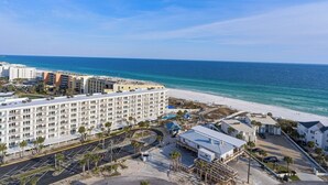 A beachfront hotel with multiple floors, a parking area, and a beach in the background. - The Adventurer’s Micro Studio at Beachview (Fort Walton Beach)