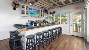 A bar area with a long counter, multiple stools, and a view through a glass door to the outside. - The Adventurer’s Micro Studio at Beachview (Fort Walton Beach)