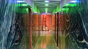 A hallway with marble walls and a polished floor, leading to a room with a red accent wall. - Hotel Sunjukti by Roh (Nagaon)