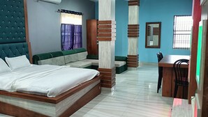 A bedroom with a bed, a green sofa, a wooden desk, and a chair. - Hotel Sunjukti by Roh (Nagaon)