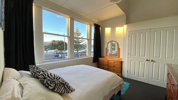 A bedroom with a bed, a dresser, a mirror, and a wardrobe.